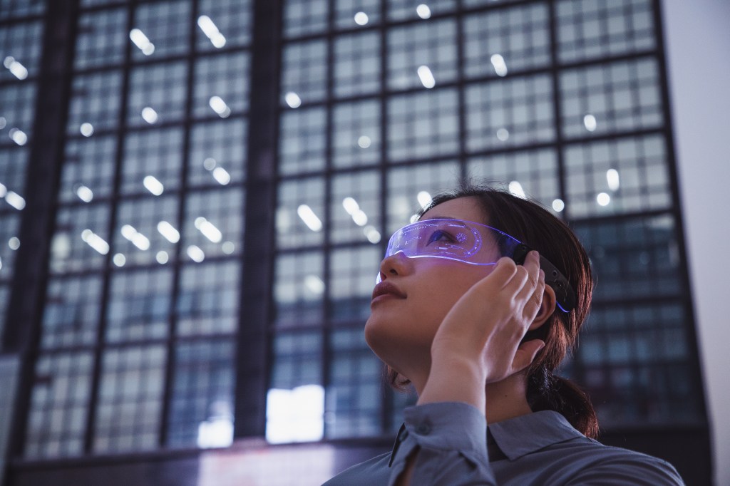 asian woman using a smart glasses in front of an office building