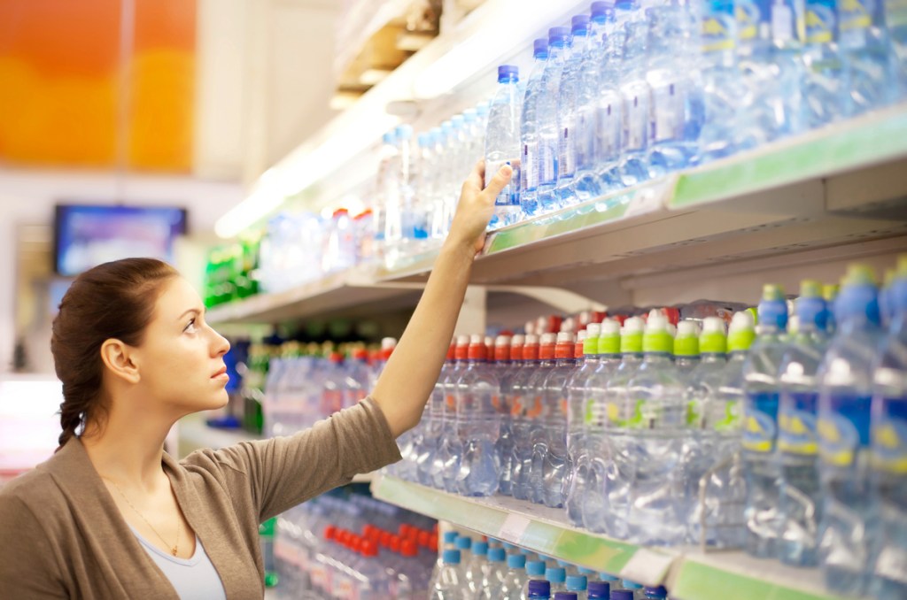 a woman grabbing a bottle of water in a supermarket