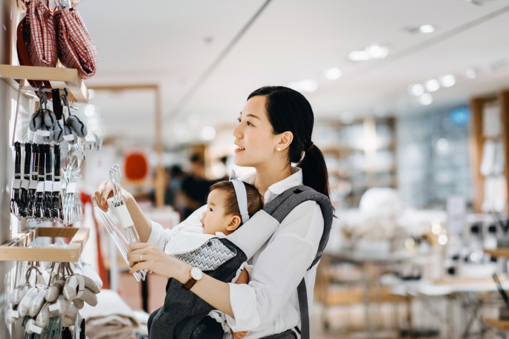 young Asian mother carrying baby girl shopping for home essentials in shop